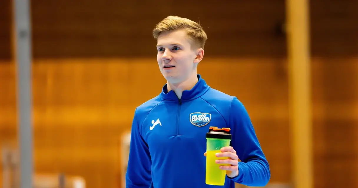 Urheilija sekoittaa palautusjuomaa shakerpullossa treenin j&auml;lkeen