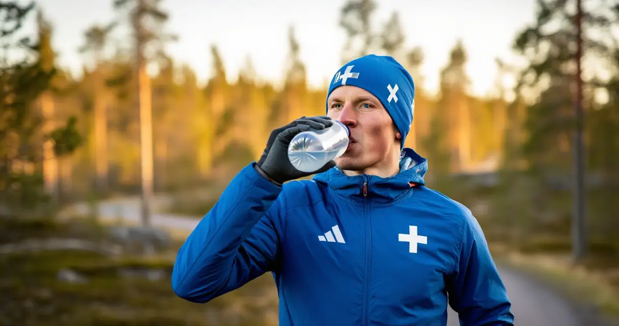 Suomalainen urheilija juo palautumisjuomaa harjoituksen j&auml;lkeen mets&auml;ss&auml;